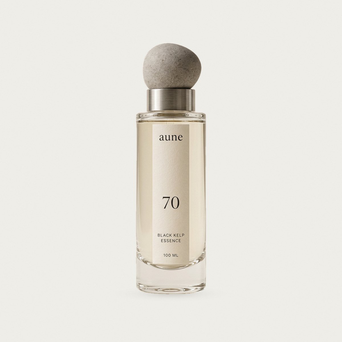 Black Kelp Essence in a clear glass bottle with a stone pebble cap, on a warm white backdrop
