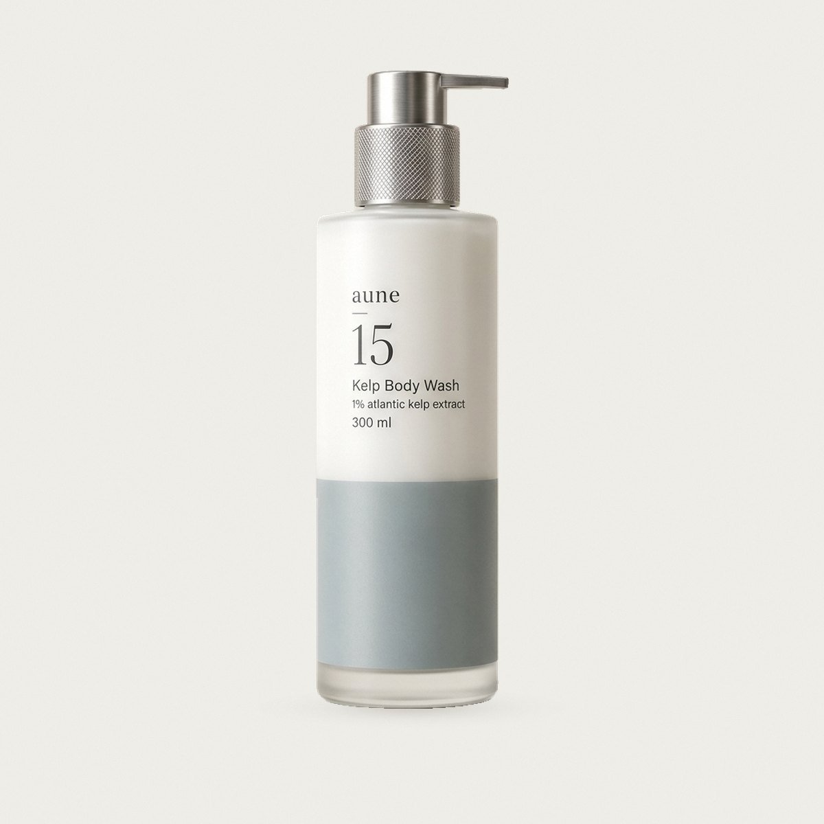 Kelp Body Wash in a white glass tall pump bottle with a sea-grey tide line, on a warm white backdrop