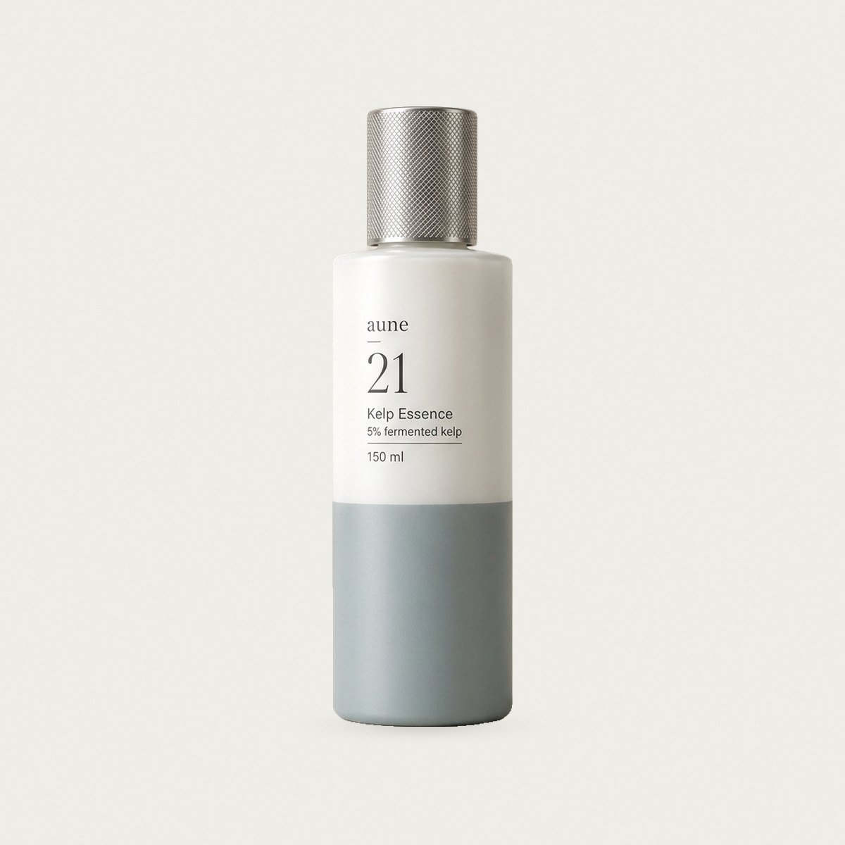 Kelp Essence in a white glass bottle with a sea-grey tide line, on a warm white backdrop