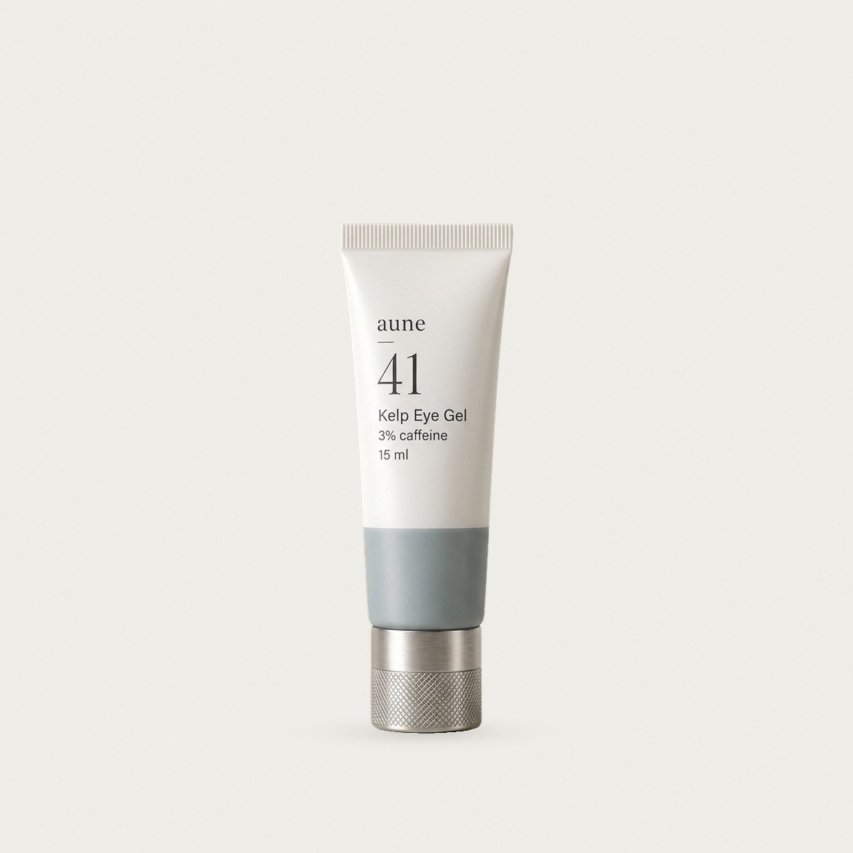Kelp Eye Gel in a white glass small tube with a sea-grey tide line, on a warm white backdrop