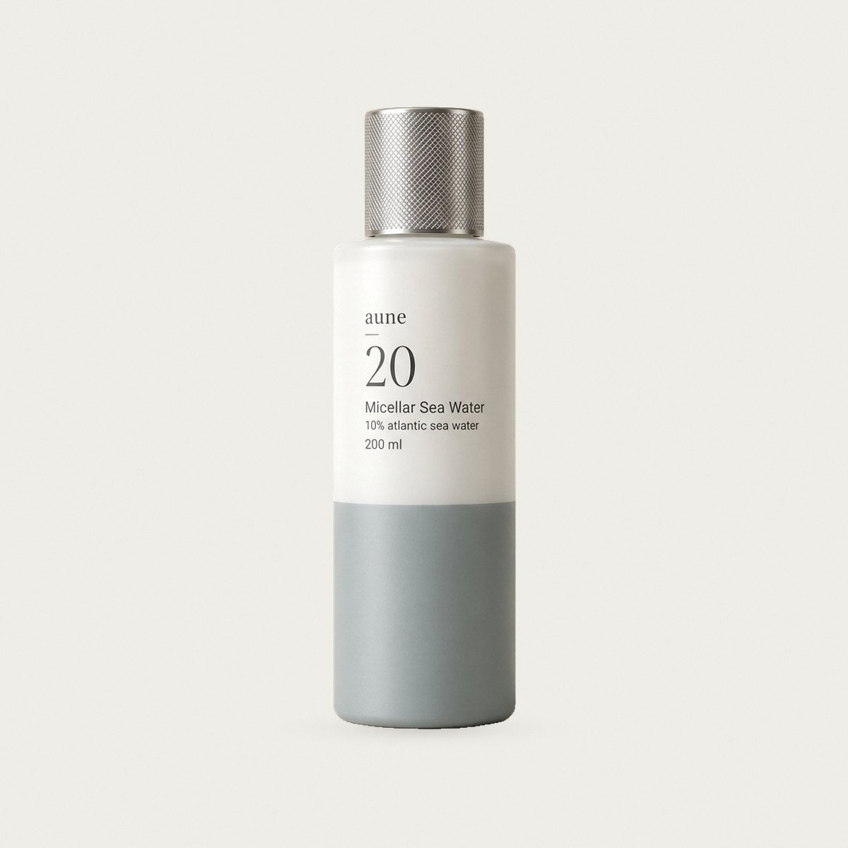 Micellar Sea Water in a white glass bottle with a sea-grey tide line, on a warm white backdrop
