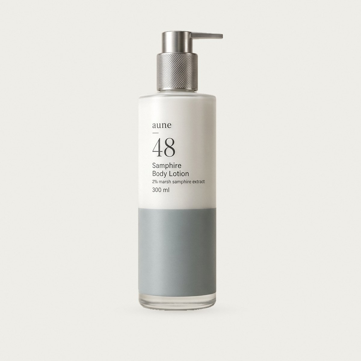 Samphire Body Lotion in a white glass tall pump bottle with a sea-grey tide line, on a warm white backdrop