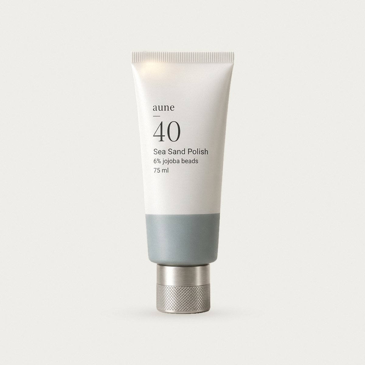 Sea Sand Polish in a white glass tube with a sea-grey tide line, on a warm white backdrop